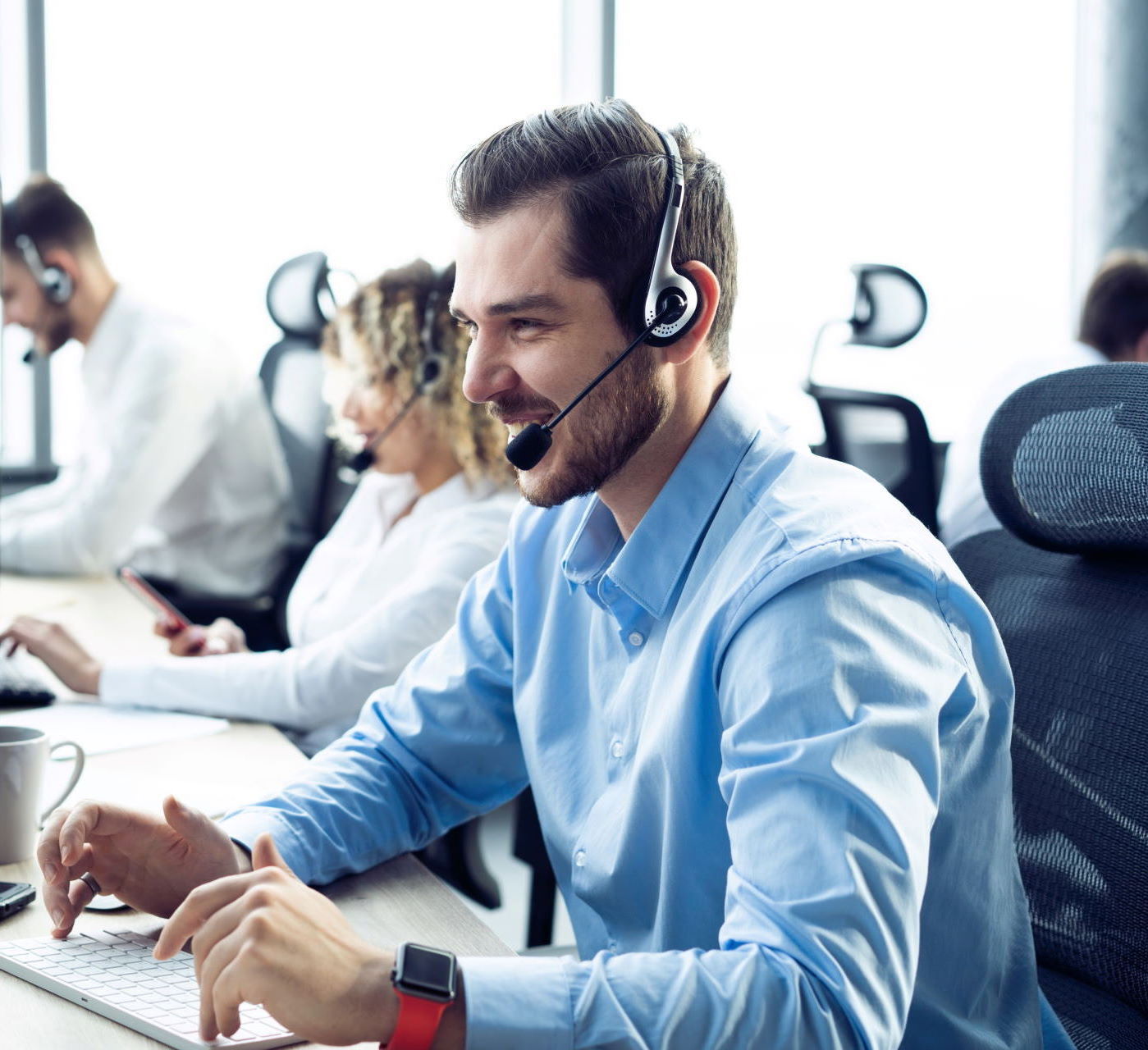 Ein Mitarbeiter im Support trägt ein Headset und lächelt während eines Telefonats mit einem Kunden