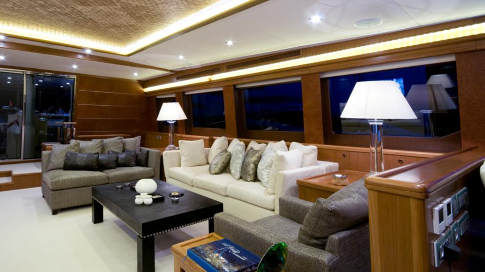Living room with upholstered sofas and lots of cushions on the Daima gulet. Evening time