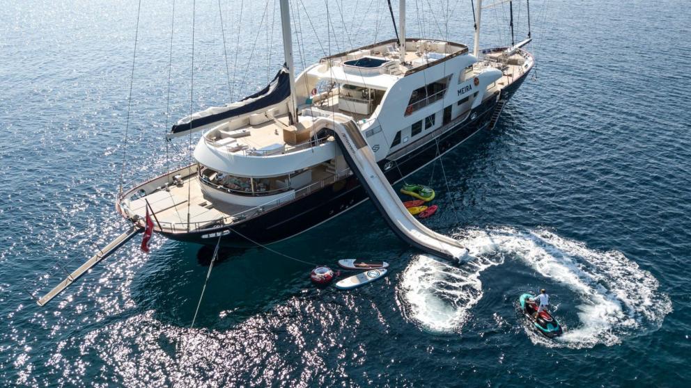 Luxury yacht Meira anchored in the sea. There is a slide for swimming fun and many water sports activities.