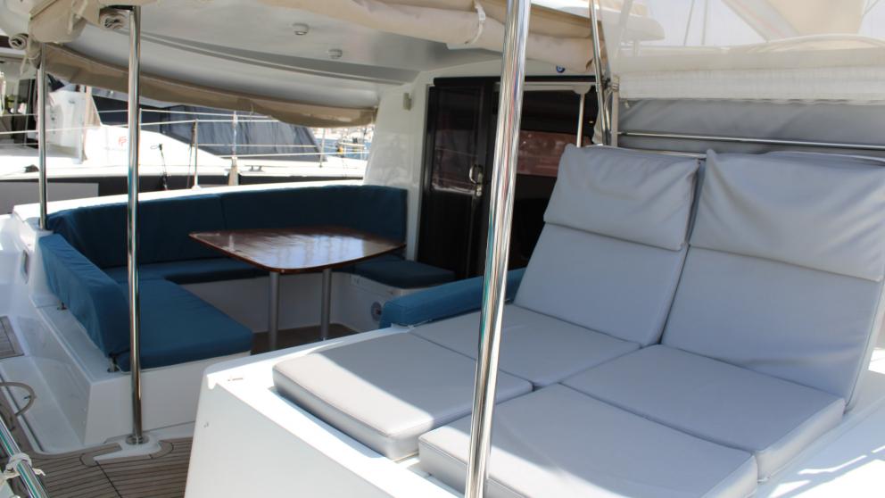 The catamaran aft cockpit seating area and two sunbathing mats offer shade.