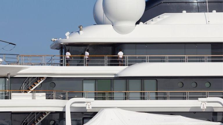 Three men perform all maintenance and inspections on a large yacht.